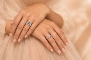 Woman is wearing a blue diamond ring and pink diamond ring