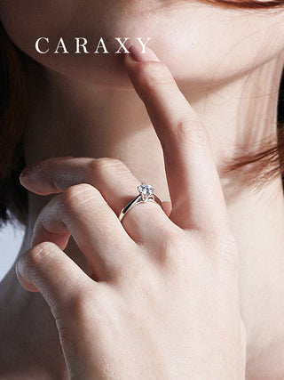 Close-up of an 18K white gold six prong solitaire ring on finger to show diamond scale.