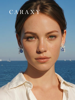 Model wearing blue sapphire and diamond drop earrings by the ocean.