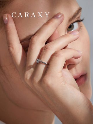 Close-up of a bypass shank floral engagement ring worn on finger to show detail.
