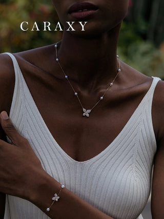 Model wearing a butterfly diamond and pearl station necklace with a matching bracelet
