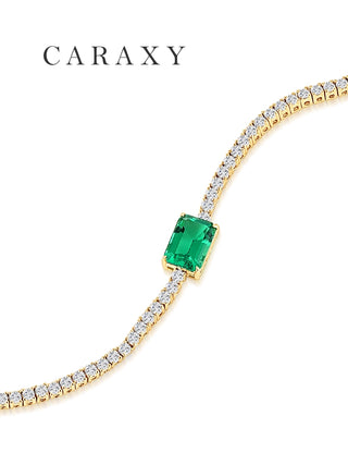 Close-up of the emerald-cut lab-grown emerald and prong-set diamonds in 18K yellow gold
