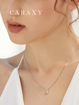 CARAXY fancy yellow lab-grown diamond halo pendant necklace in 18K white gold shown in an elegant styling shot.