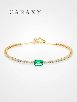 Front view of an 18K yellow gold tennis bracelet with a lab-grown emerald and lab-grown diamonds