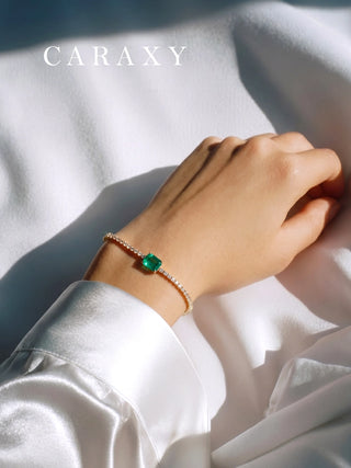 Lab-grown emerald and diamond tennis bracelet worn on the wrist in natural light