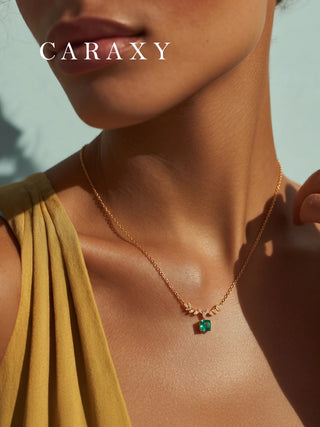 CARAXY Leaf Series emerald necklace on model, featuring an asscher cut green emerald and 18K yellow gold chain