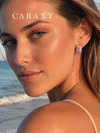Fancy yellow lab-grown diamond feather earrings worn by the sea in warm natural light