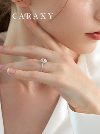 Close-up on finger showing the elegant profile of an oval diamond ring with cathedral setting.
