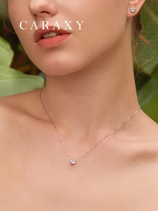 Model wearing dainty lab grown diamond solitaire necklace with matching diamond stud earrings in 18K white gold.
