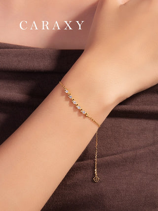 Close-up of a dainty five-stone round lab grown diamond bracelet in 18K yellow gold on wrist.