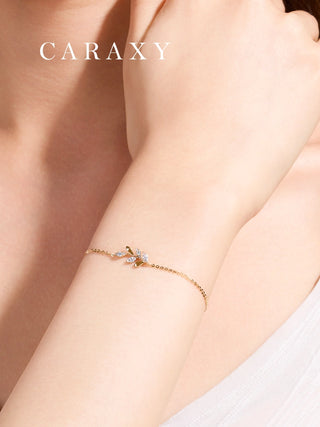 Woman wearing a dainty leaf-inspired lab grown diamond bracelet in 18K yellow gold.