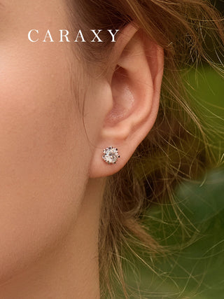 Close-up of delicate winter-inspired diamond earrings worn on the ear.