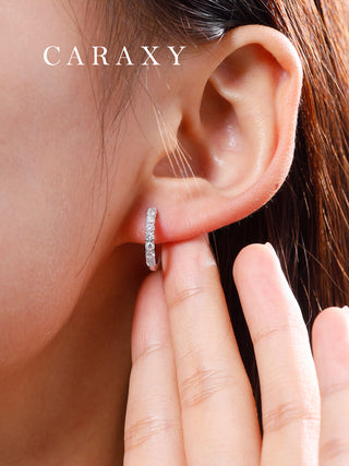 Model wearing diamond huggie earrings in a close-up ear view.