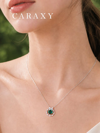 Close-up of an emerald and diamond pendant necklace worn at the neckline