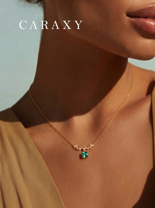 odel wearing an emerald May birthstone necklace with Asscher cut lab created emerald and delicate leaf motif.