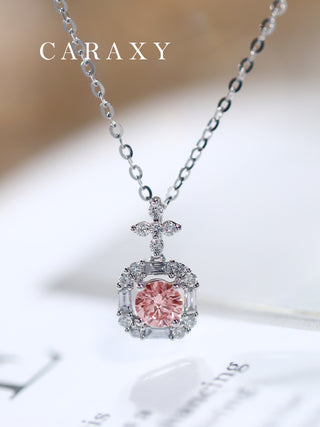 Close-up of a fancy pink lab-grown diamond halo pendant necklace in 18K white gold on a surface.