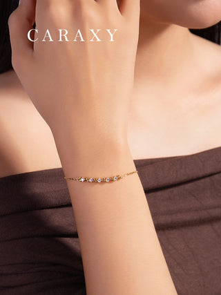 Woman wearing a five-stone round lab grown diamond bracelet in 18K yellow gold with leaf-inspired accents.