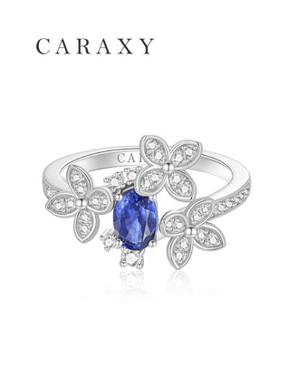 Front view of a floral blue sapphire bypass ring with micro pavé diamond accents.
