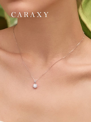 Close-up of a woman wearing a floral diamond necklace with a round center stone and halo of brilliant diamonds.