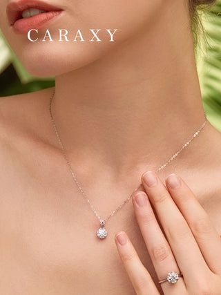 Woman wearing a floral diamond necklace with matching ring set, featuring a round center stone surrounded by brilliant diamonds.