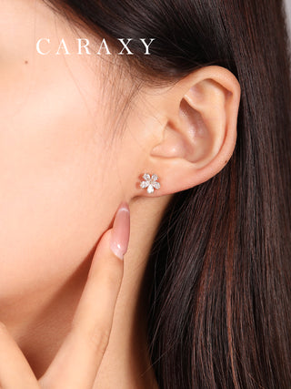 Model wearing flower-shaped diamond studs in a close-up ear view.