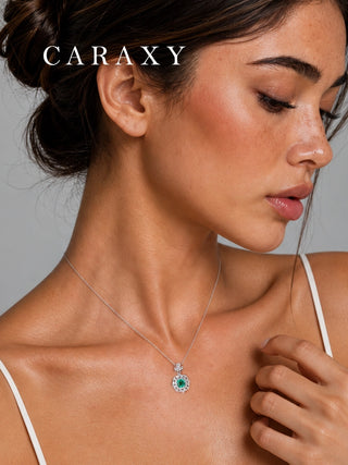Close-up of a muzo-green gemstone diamond pendant necklace worn at the neckline