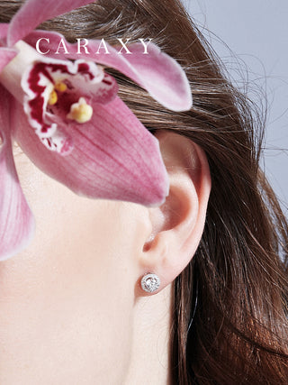 Round halo lab-grown diamond stud earrings worn with soft pink orchid styling.