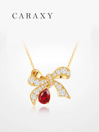 Lab created ruby bow pendant necklace in 18K yellow gold with pear ruby drop and lab grown diamond accents.