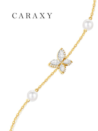 Close-up of a lab-grown diamond butterfly charm and freshwater pearls on an 18K gold chain