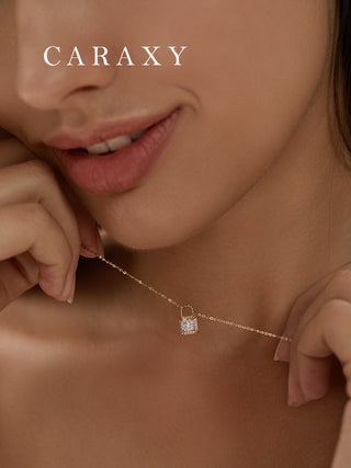 Model wearing a lab grown diamond lock pendant necklace in 18K yellow gold with a round brilliant center stone and halo detail.