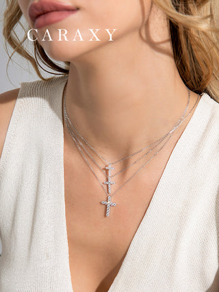 Model wearing layered white gold diamond cross necklaces styled for a modern everyday jewelry look.