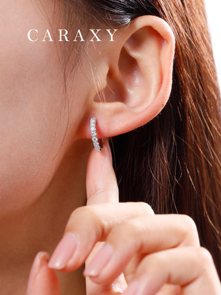 Minimal diamond huggie hoops shown on model with soft natural light.