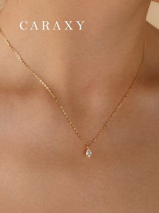Minimalist pear shaped lab grown diamond pendant necklace in 18K yellow gold shown on a model.
