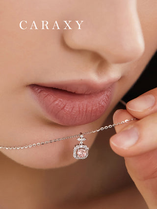 Model holding a fancy pink lab-grown diamond halo pendant necklace in close view.