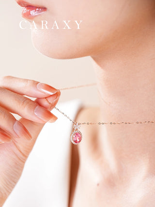 Model holding an oval Padparadscha sapphire and diamond halo necklace