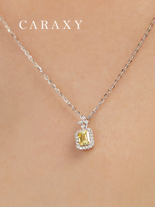 Model wearing an emerald-cut fancy yellow diamond halo pendant necklace in close view.