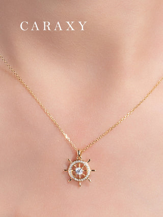 Close-up of a model wearing a nautical diamond necklace in 18K yellow gold with a ship wheel pendant and round brilliant center stone.