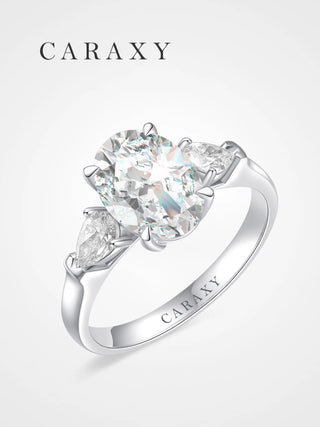 Oval cut three-stone engagement ring featuring pear-shaped side diamonds in 18K white gold.
