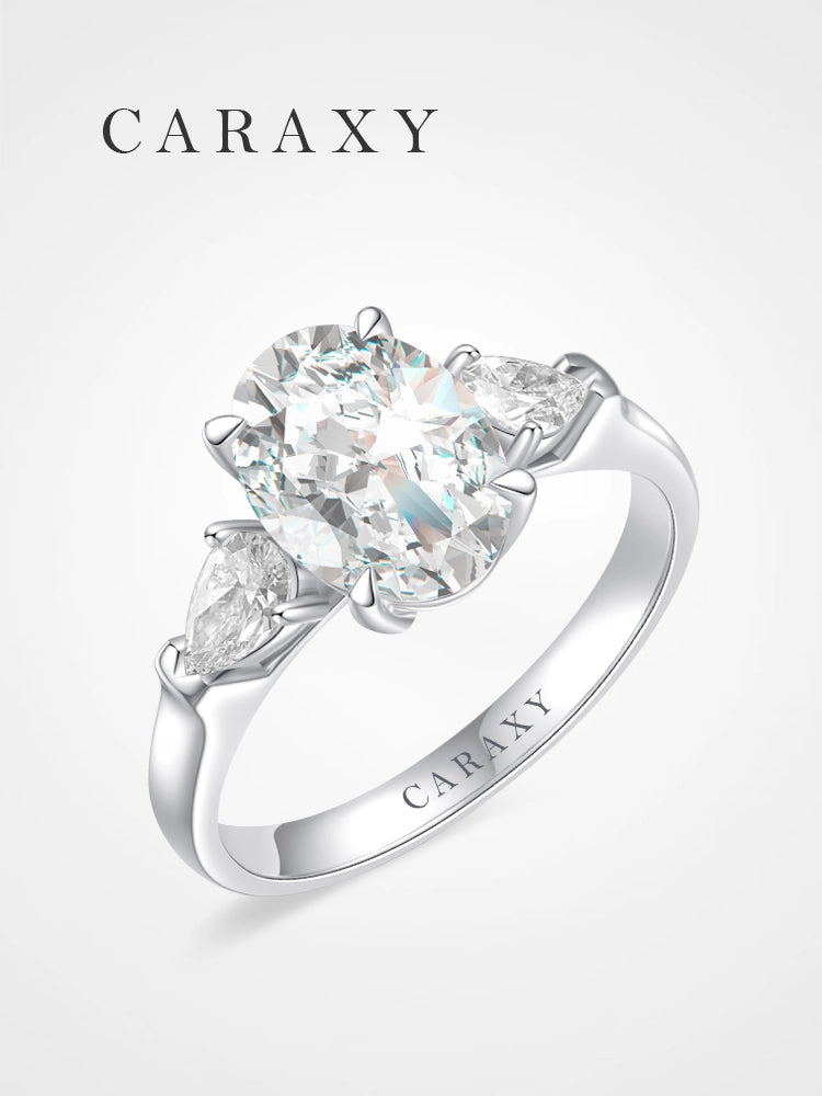 Oval cut three-stone engagement ring featuring pear-shaped side diamonds in 18K white gold.