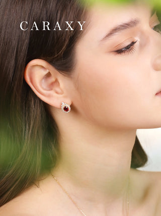 Close-up of ruby and diamond halo stud earrings in yellow gold.