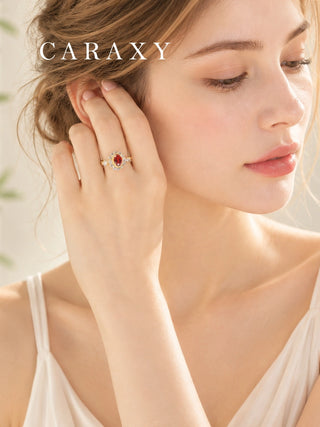 Woman wearing an oval ruby and diamond halo engagement ring in yellow gold