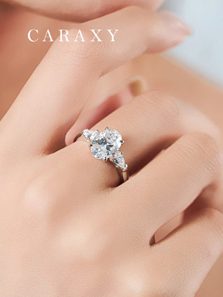 Lifestyle view of an oval cut three-stone engagement ring worn on finger to show scale.