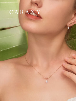 Model wearing a pear-shaped diamond drop necklace in 18K yellow gold with matching earrings from the same series.