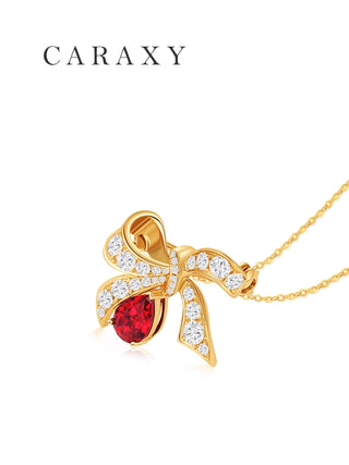 Close-up of pear lab created ruby bow pendant with round lab grown diamonds in 18K yellow gold.