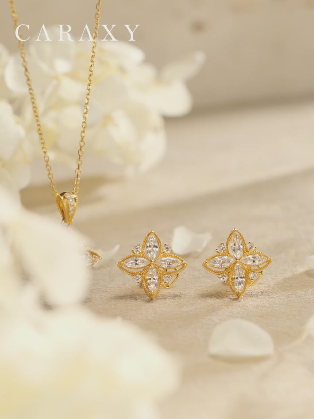 Close-up video of four-petal floral lab grown diamond stud earrings and matching necklace in 18K yellow gold, showing marquise diamond petals, side profile, and beaded design details.