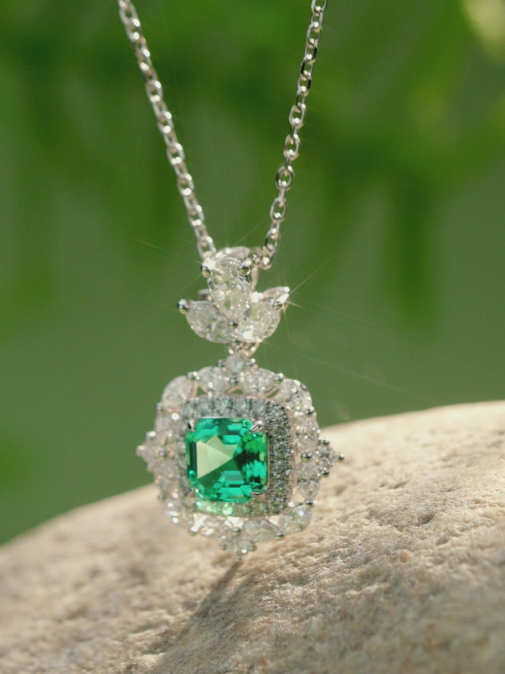 Asscher-cut gemstone and lab grown diamond pendant necklace in 18K white gold shown from multiple angles, highlighting the diamond halo and green centre stone
