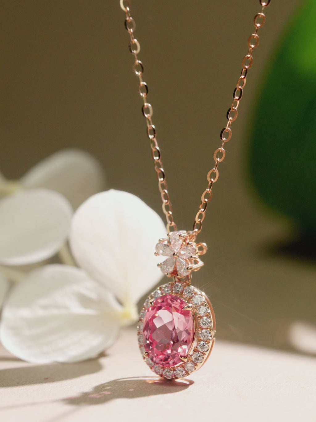 Multi-angle view of a Padparadscha sapphire halo necklace in 18K rose gold.