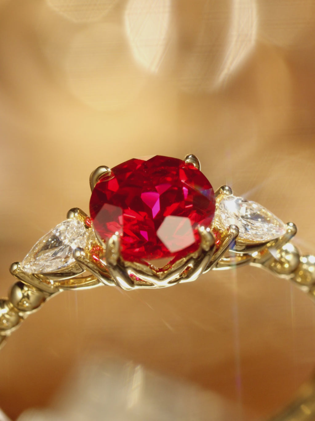 Round lab grown ruby and pear diamond ring in 18K yellow gold shown from multiple angles, highlighting the beaded shank and leaf-inspired details