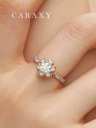 Close-up of CARAXY round cut floral halo diamond ring worn on hand, featuring a yellow gold and white gold design