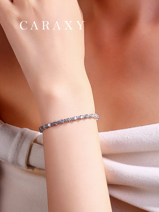 Close-up of a round diamond X-link tennis bracelet worn on the wrist.
